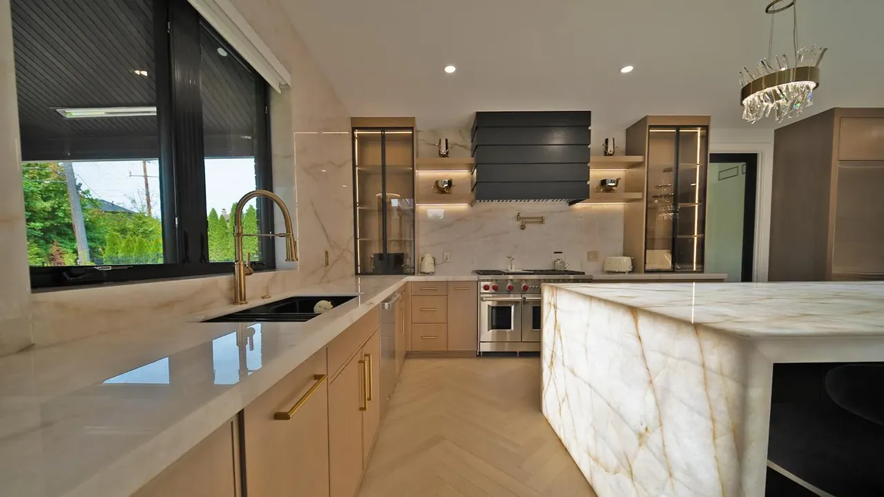 White oak kitchen with an onyx waterfall island, glass upper cabinets and a black range hood by Mason Oak Carpentry in Detroit, MI