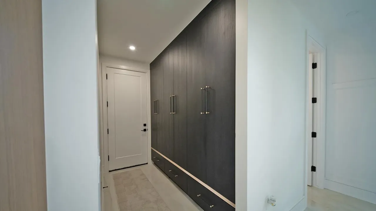 Mudroom wall of tall charcoal cabinets with brass pulls by Mason Oak Carpentry in Detroit, MI