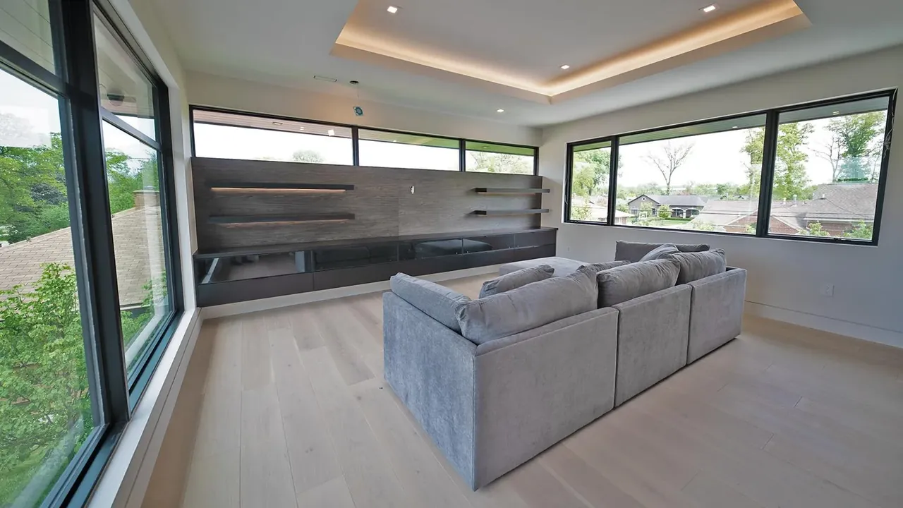 Floating media wall with a stone panel and shelving in a bright family room by Mason Oak Carpentry in Detroit, MI