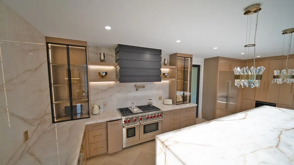 Light wood kitchen with lit glass display cabinets and a black slatted range hood by Mason Oak Carpentry in Detroit, MI