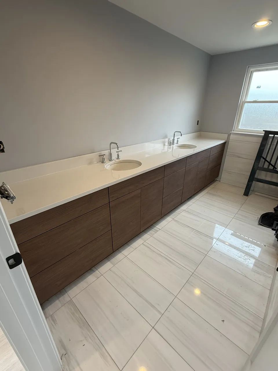 Long walnut double vanity with a white stone top by Mason Oak Carpentry in Detroit, MI
