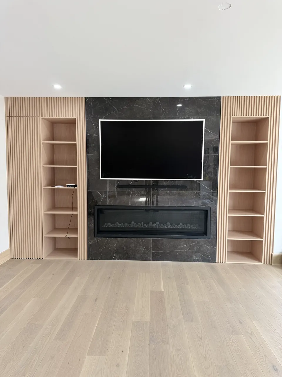 TV wall with a linear fireplace, fluted panels and open shelves by Mason Oak Carpentry in Detroit, MI
