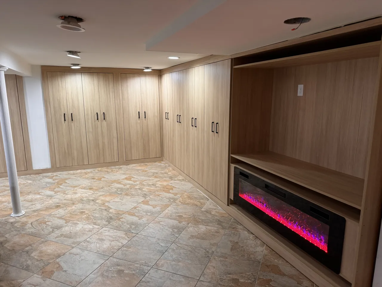 Basement built-ins with wood wardrobes and a fireplace media unit by Mason Oak Carpentry in Detroit, MI