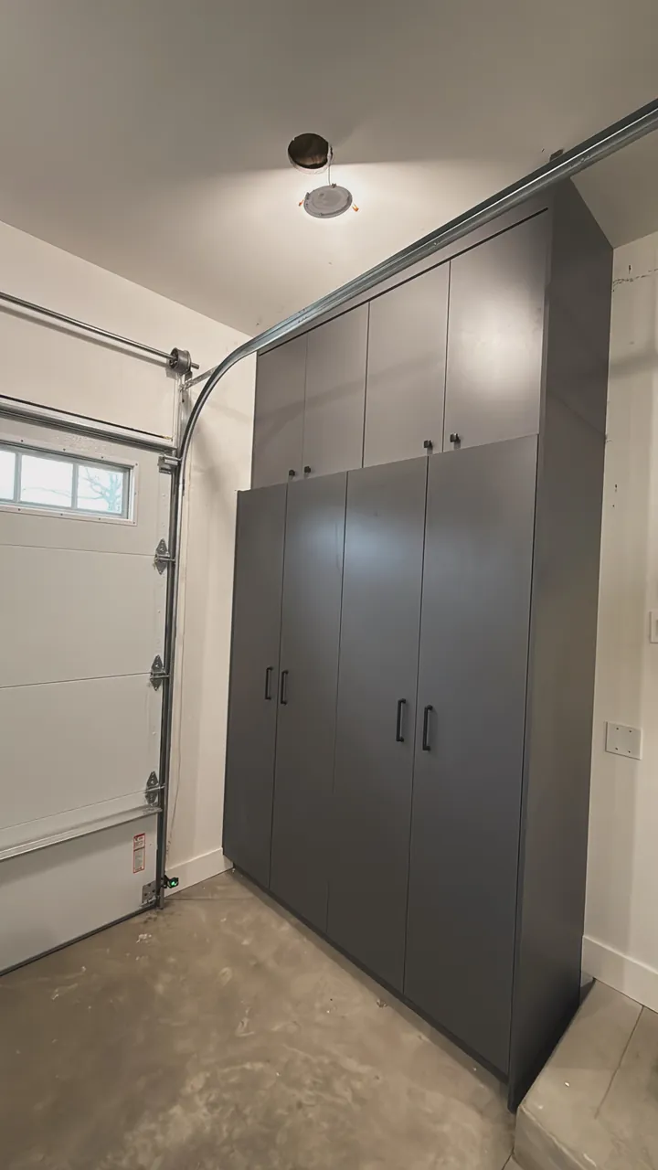 Gray garage storage cabinets beside the garage door by Mason Oak Carpentry in Detroit, MI