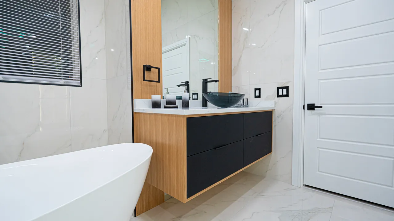Oak and black floating vanity with a glass vessel sink and a lit mirror by Mason Oak Carpentry in Detroit, MI