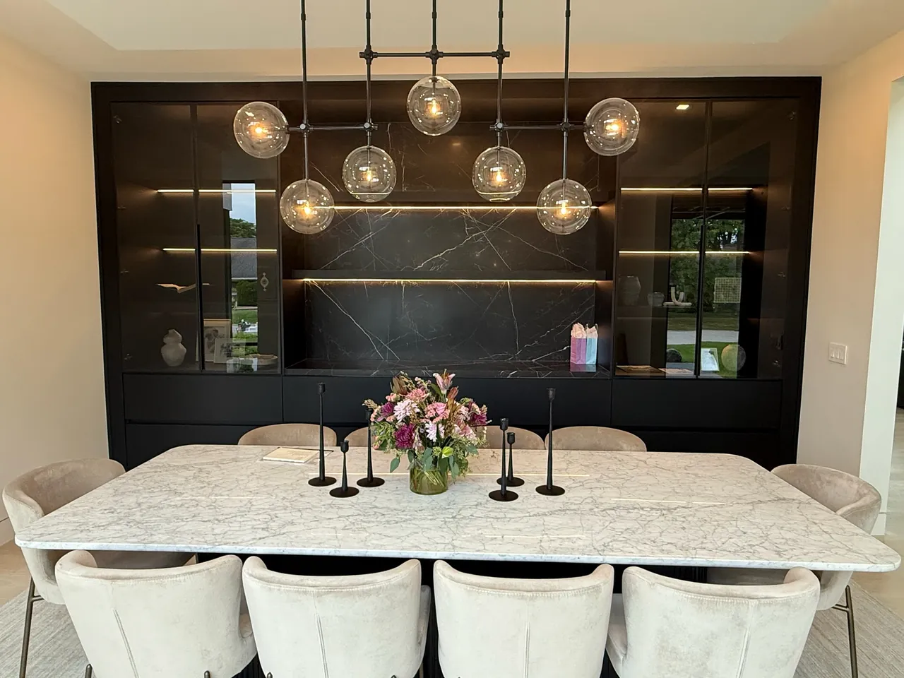 Dining room with a black built-in wall unit, lit glass display cabinets and a stone feature panel by Mason Oak Carpentry in Detroit, MI