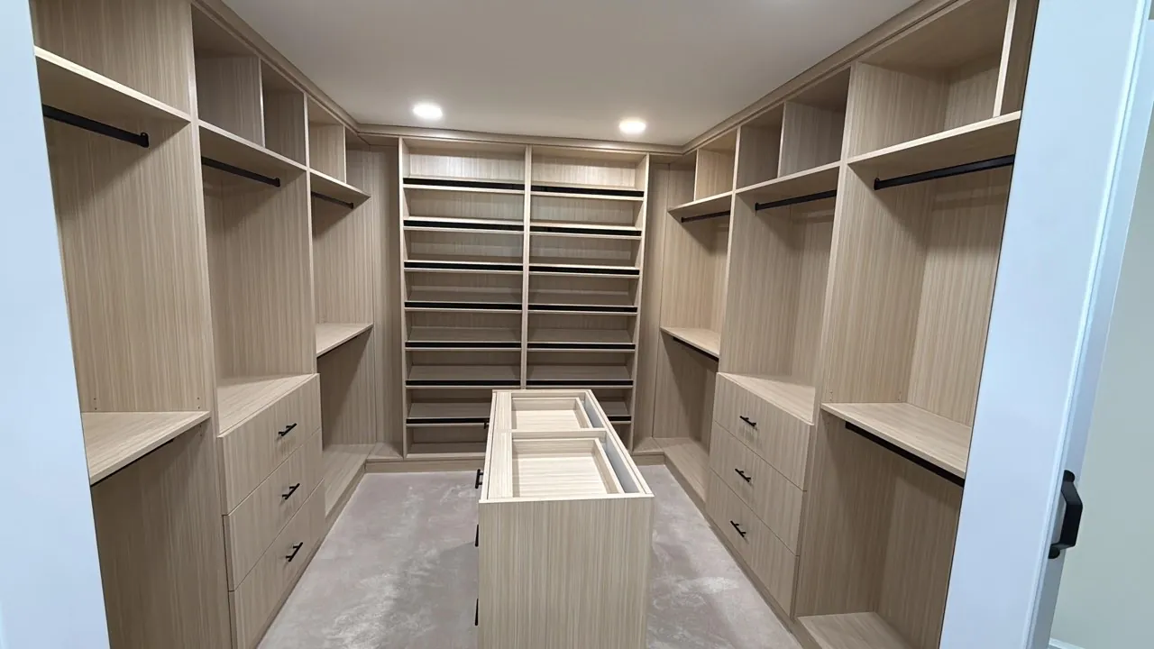 Light wood walk-in closet with open shelving and a center island by Mason Oak Carpentry in Detroit, MI