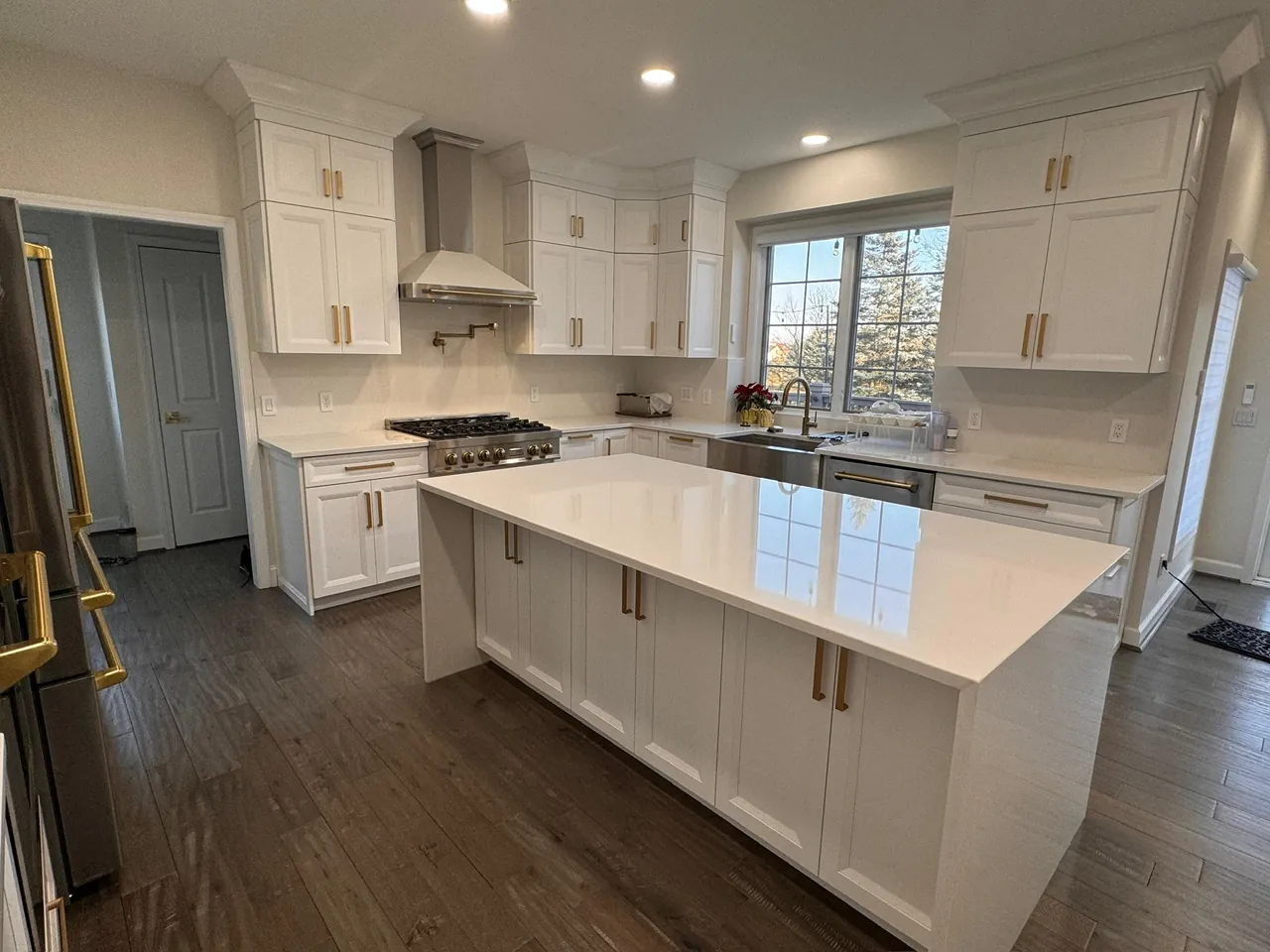 White shaker kitchen with a waterfall island, brass pulls and a stainless range hood by Mason Oak Carpentry in Detroit, MI