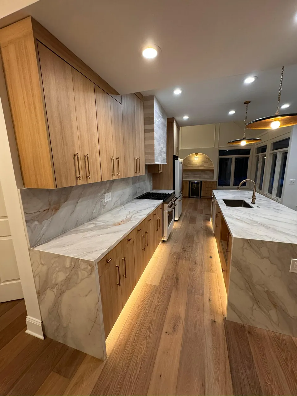 Oak kitchen with a marble waterfall island and LED lighting under the cabinets by Mason Oak Carpentry in Detroit, MI