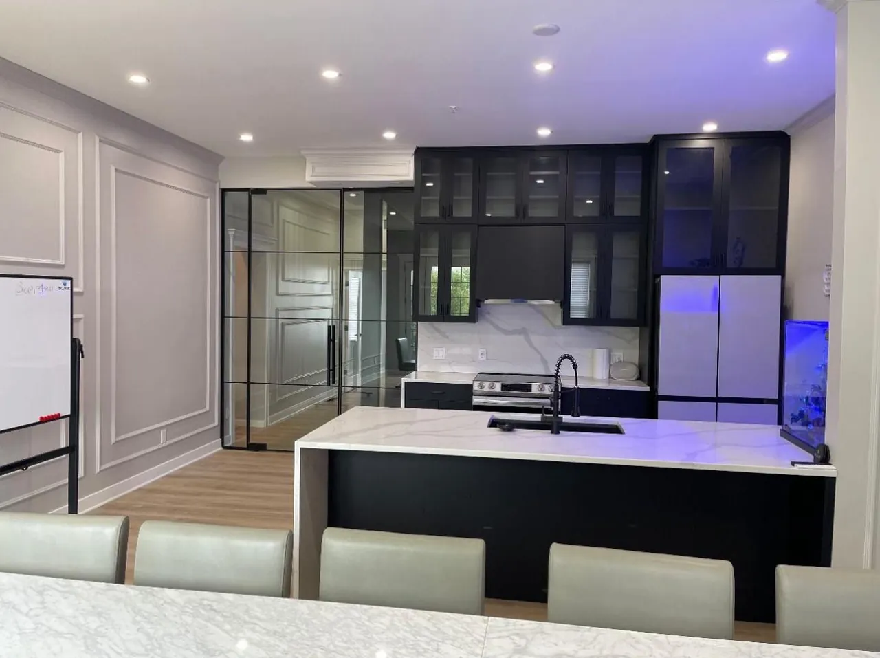 Black island with a white waterfall countertop and black glass-front upper cabinets by Mason Oak Carpentry in Detroit, MI