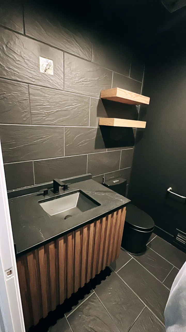 Powder room vanity with a walnut slat front, a black stone top and floating shelves by Mason Oak Carpentry in Detroit, MI