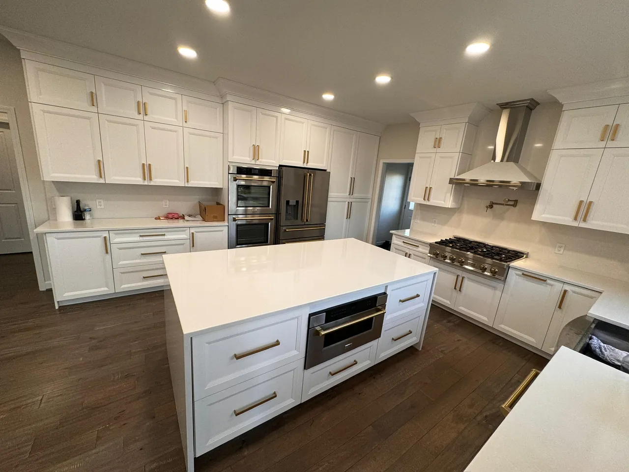White kitchen island with a built-in microwave drawer and brass pulls by Mason Oak Carpentry in Detroit, MI