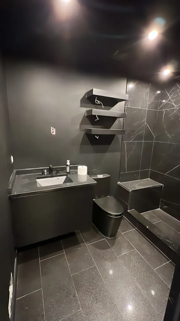 Black floating vanity with stacked floating shelves in a black stone powder room by Mason Oak Carpentry in Detroit, MI