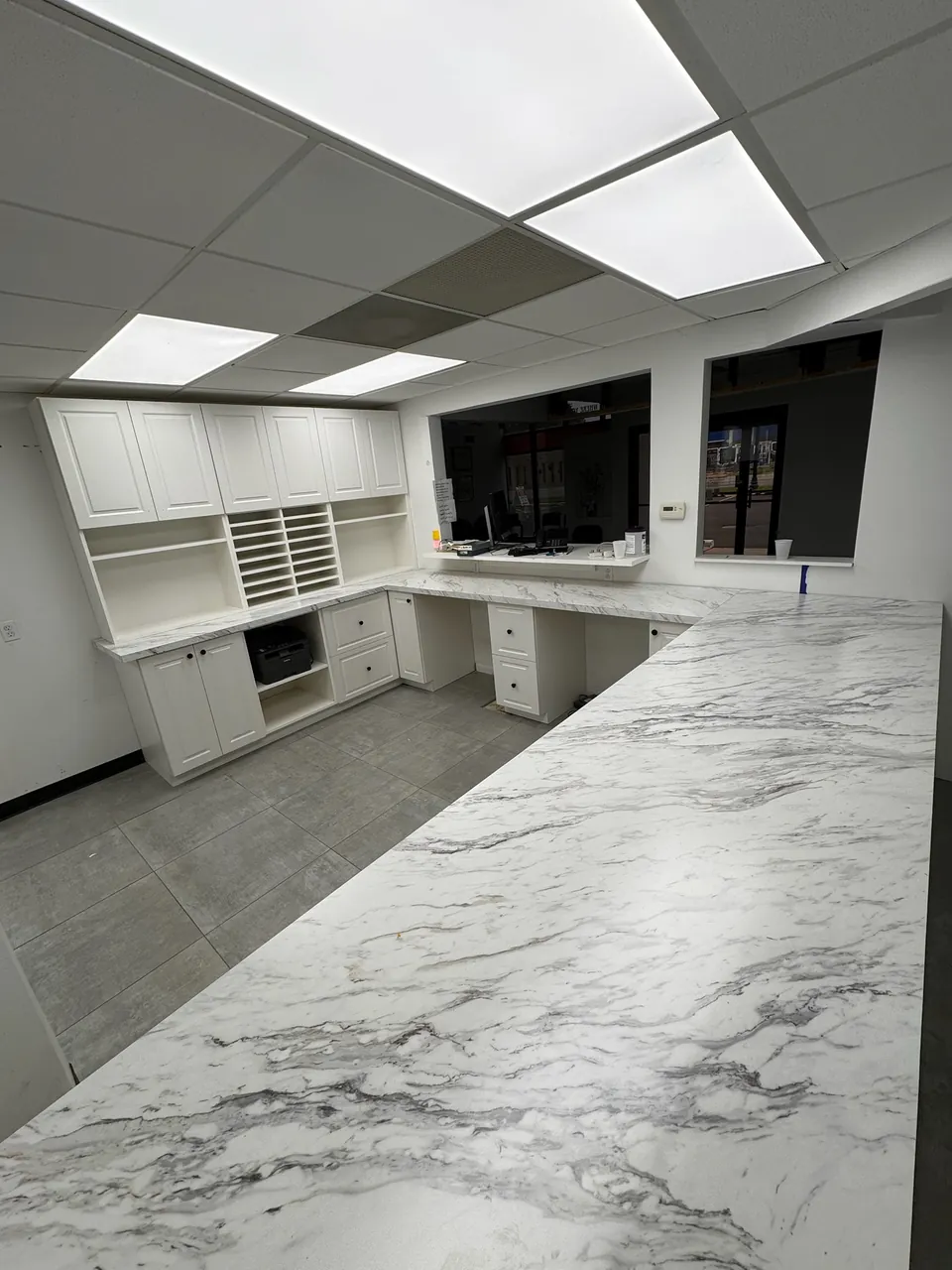 Office built-ins with white cabinets, cubby storage and a long marble countertop by Mason Oak Carpentry in Detroit, MI