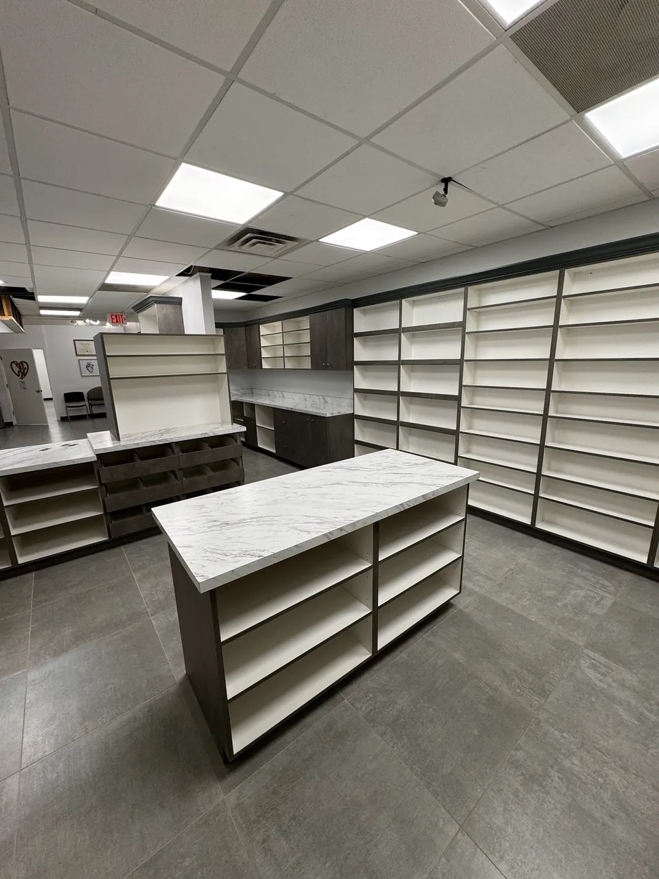 Retail fit-out with wall-to-wall white shelving and a center display island by Mason Oak Carpentry in Detroit, MI