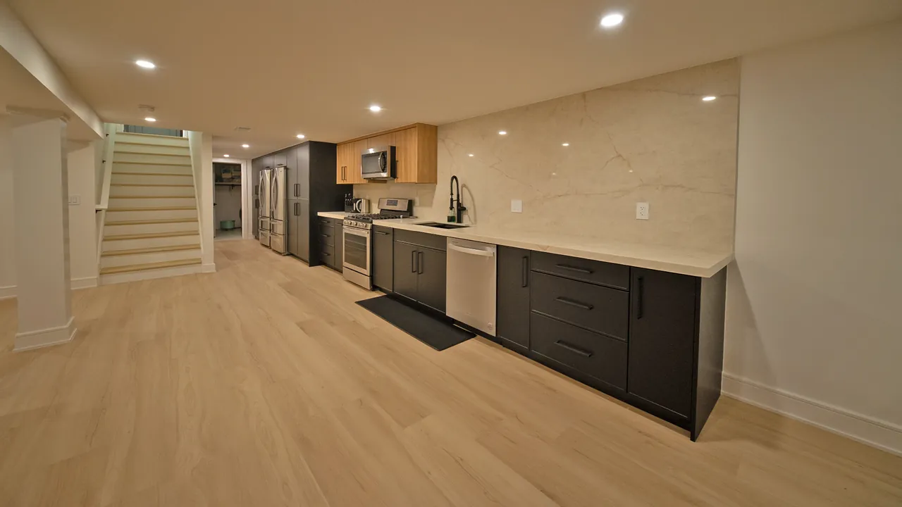 Basement kitchen with charcoal cabinets, a stone backsplash and a light wood upper run by Mason Oak Carpentry in Detroit, MI