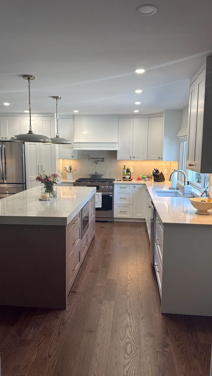 White kitchen with a dark island, pendant lights and a stone countertop by Mason Oak Carpentry in Detroit, MI