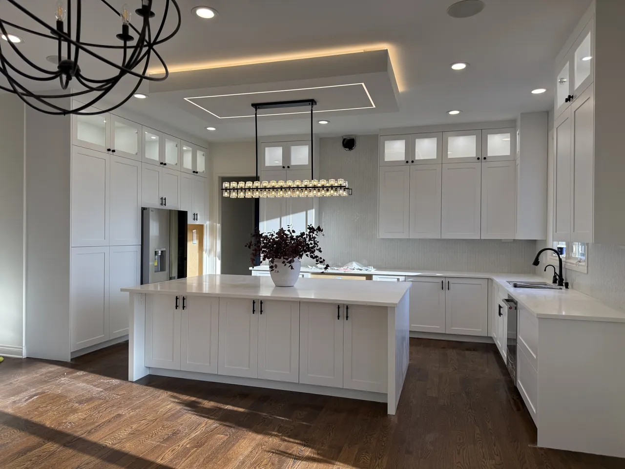 White kitchen with a large island, glass top cabinets and a tray ceiling by Mason Oak Carpentry in Detroit, MI