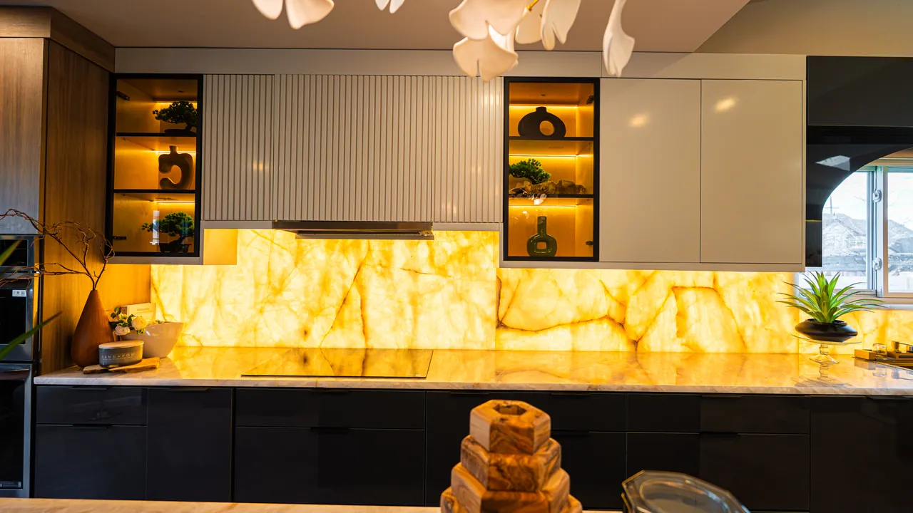 Black kitchen with a backlit onyx backsplash and lit glass shelves by Mason Oak Carpentry in Detroit, MI