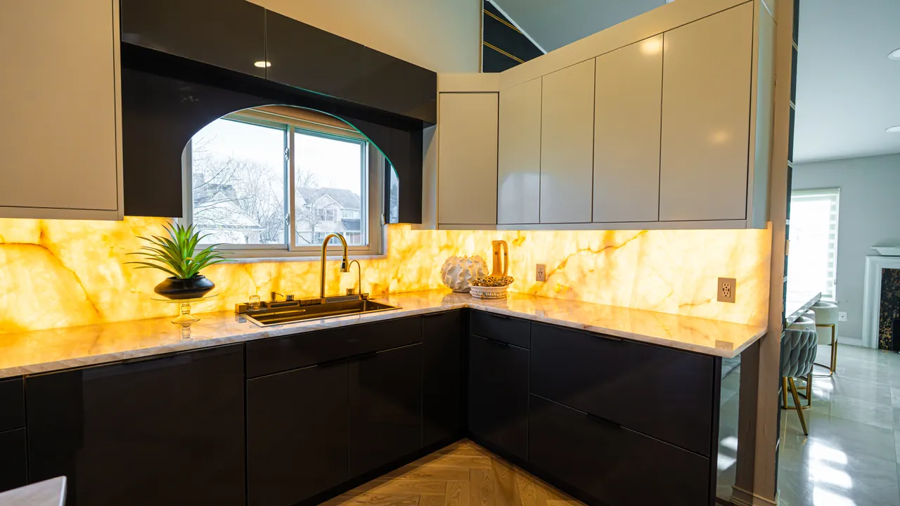 Black L-shaped kitchen with a backlit onyx backsplash under a window by Mason Oak Carpentry in Detroit, MI