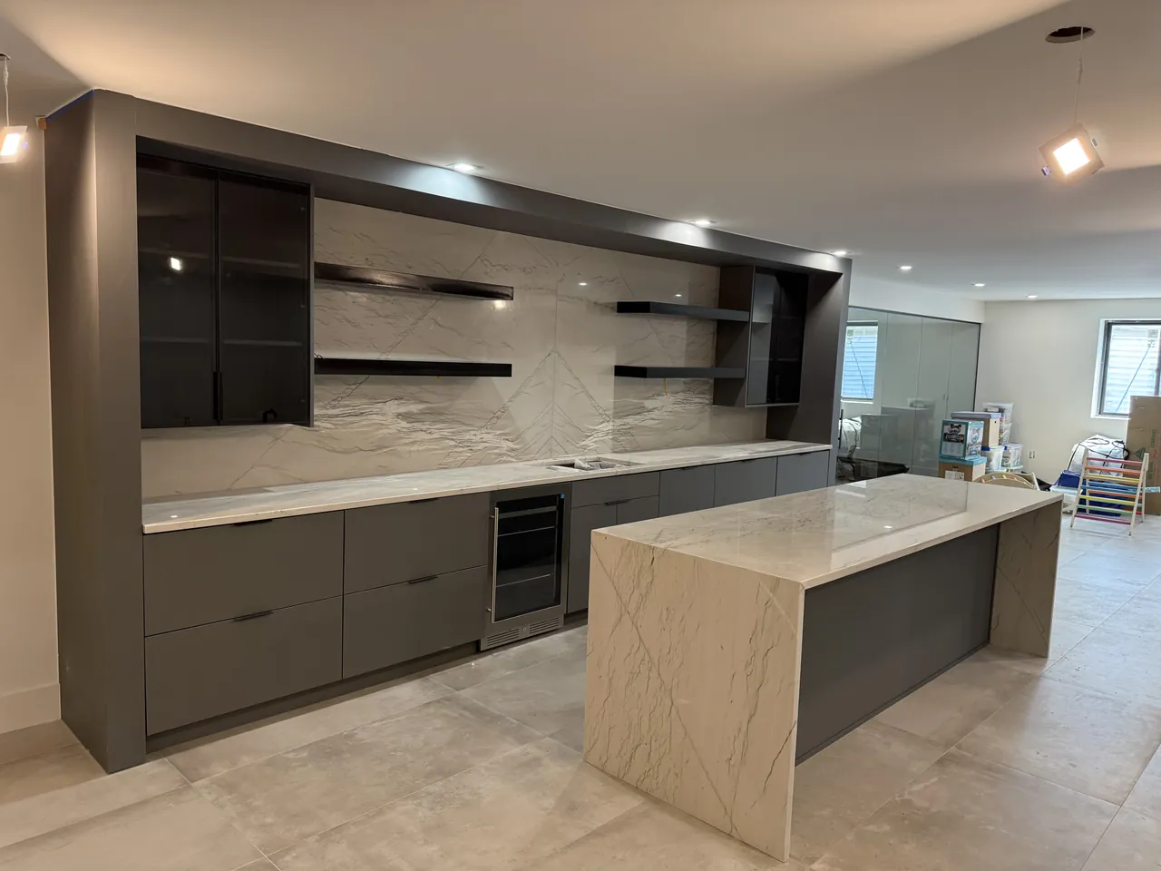 Gray kitchen with a waterfall island, floating shelves and a stone backsplash by Mason Oak Carpentry in Detroit, MI