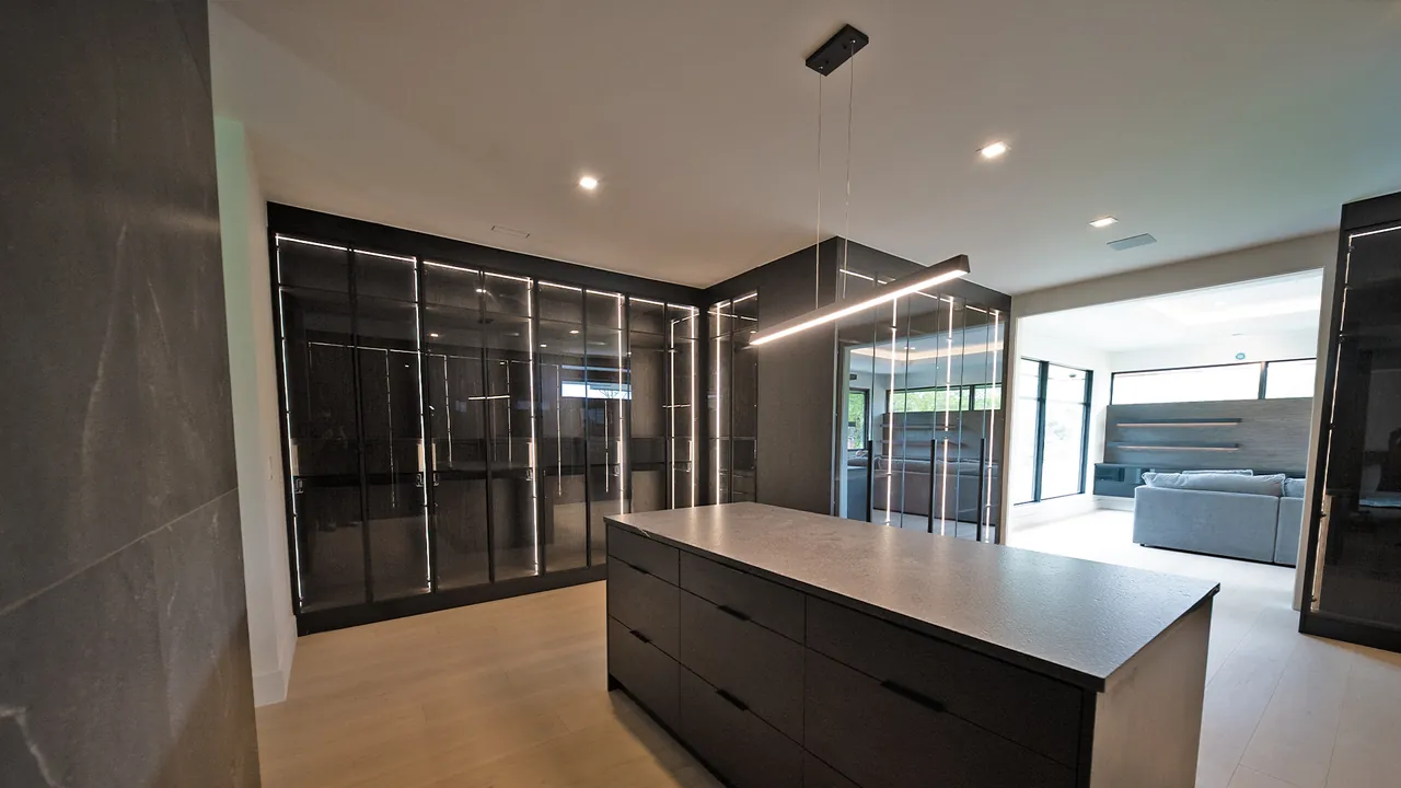 Walk-in closet with black glass wardrobes and a drawer island by Mason Oak Carpentry in Detroit, MI