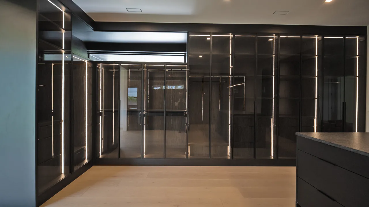 Black glass walk-in closet with LED strip lighting by Mason Oak Carpentry in Detroit, MI