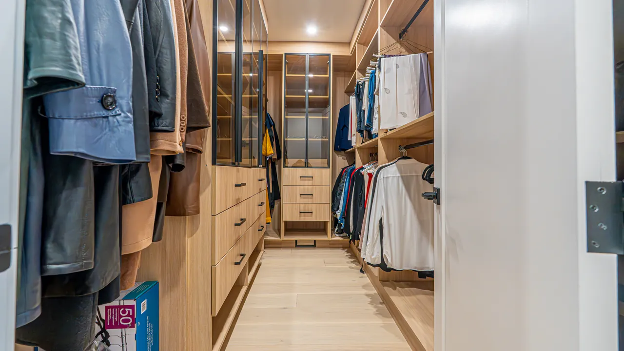 Wood walk-in closet with glass-front cabinets and drawers by Mason Oak Carpentry in Detroit, MI