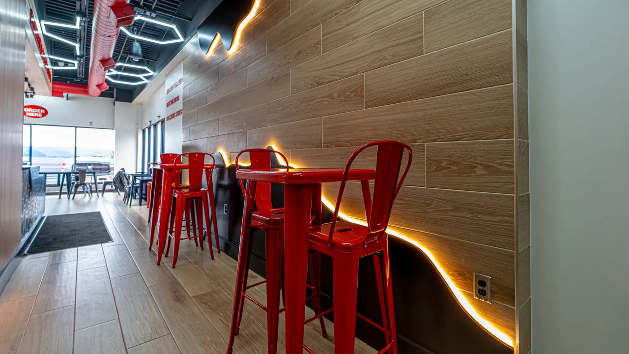 Restaurant dining area with a wood plank wall and red bar stools by Mason Oak Carpentry in Detroit, MI