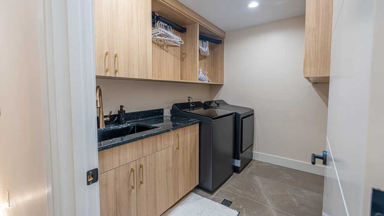 Laundry room with light wood cabinets, a black countertop and a utility sink by Mason Oak Carpentry in Detroit, MI