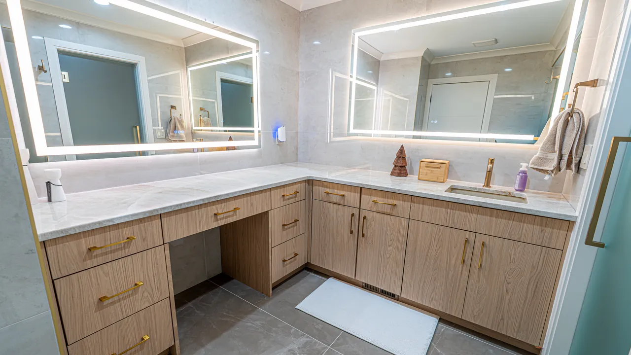 Light wood double vanity with a makeup desk and lit mirrors by Mason Oak Carpentry in Detroit, MI
