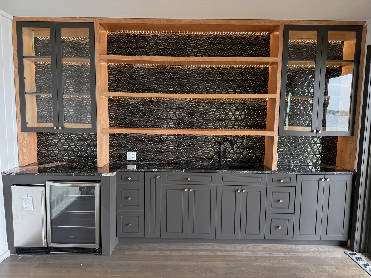 Wet bar with lit glass cabinets, open wood shelves and a wine fridge by Mason Oak Carpentry in Detroit, MI