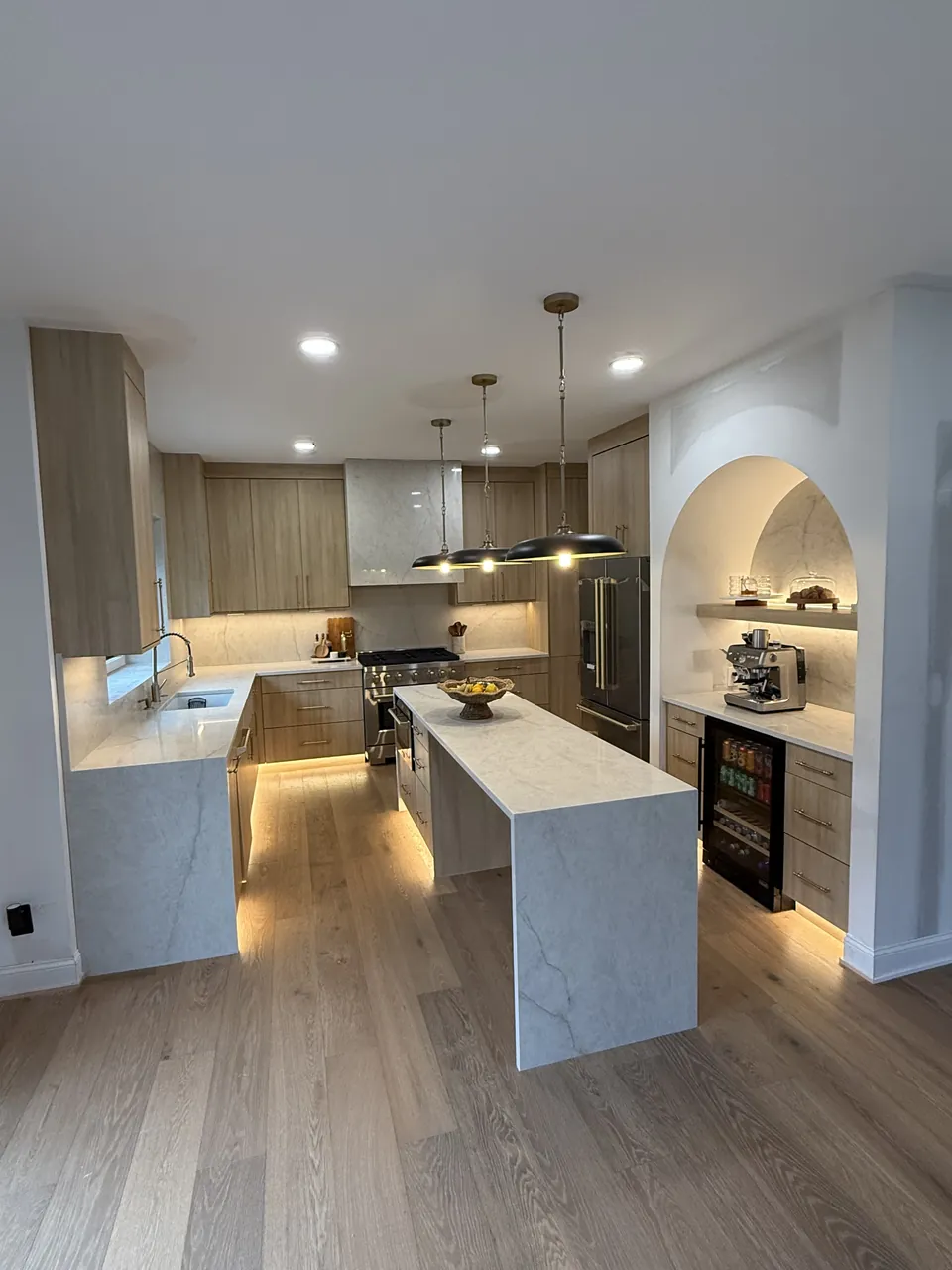 Two-tone kitchen with a waterfall island, under-cabinet lighting and an arched niche by Mason Oak Carpentry in Detroit, MI