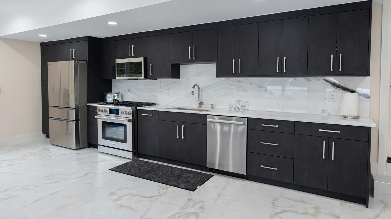 Black kitchen with a full run of upper cabinets and a marble-look floor by Mason Oak Carpentry in Detroit, MI