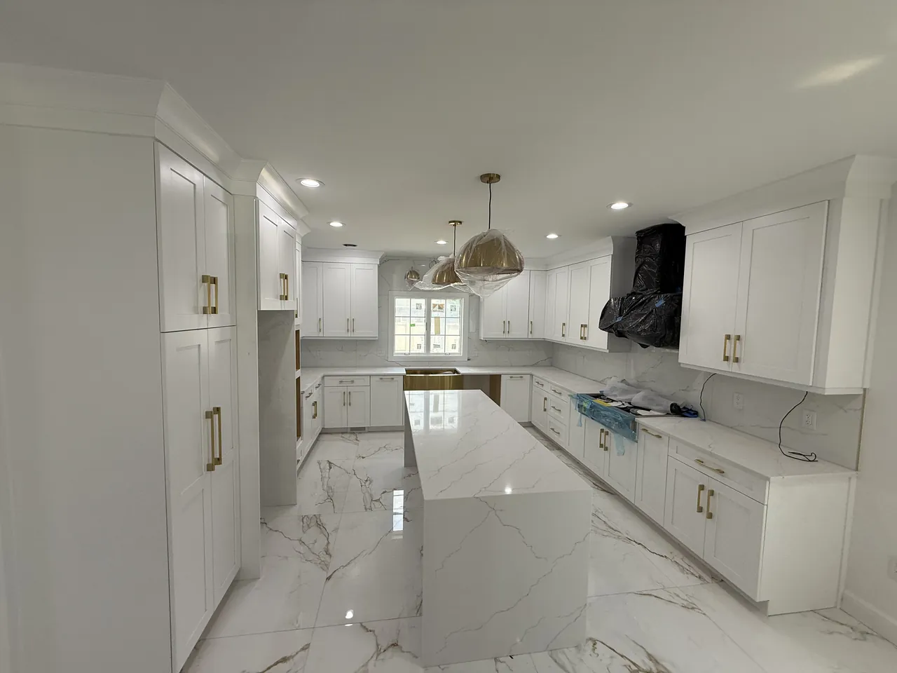 White shaker kitchen with a long marble island and brass pulls by Mason Oak Carpentry in Detroit, MI