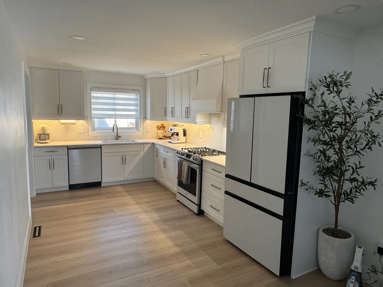 White kitchen with under-cabinet lighting and a white fridge by Mason Oak Carpentry in Detroit, MI