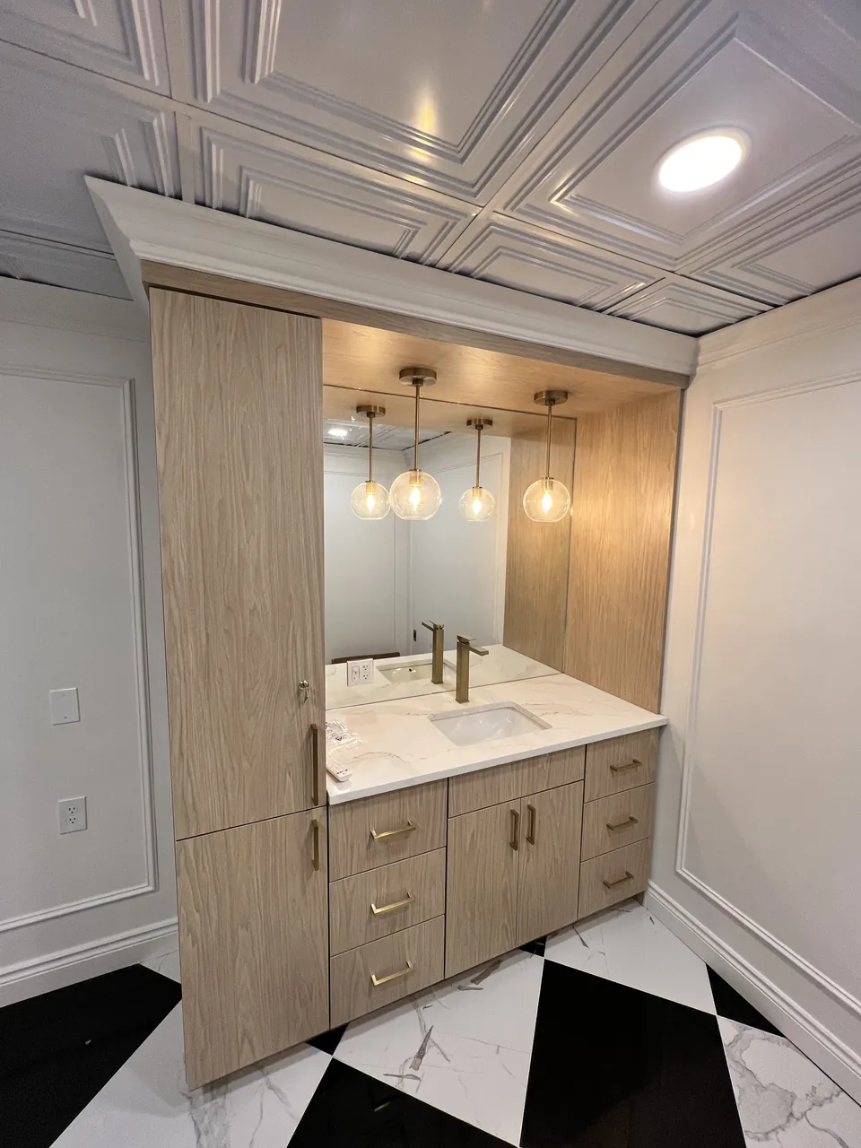 Light wood vanity cabinet with a tall linen tower in a commercial restroom by Mason Oak Carpentry in Detroit, MI