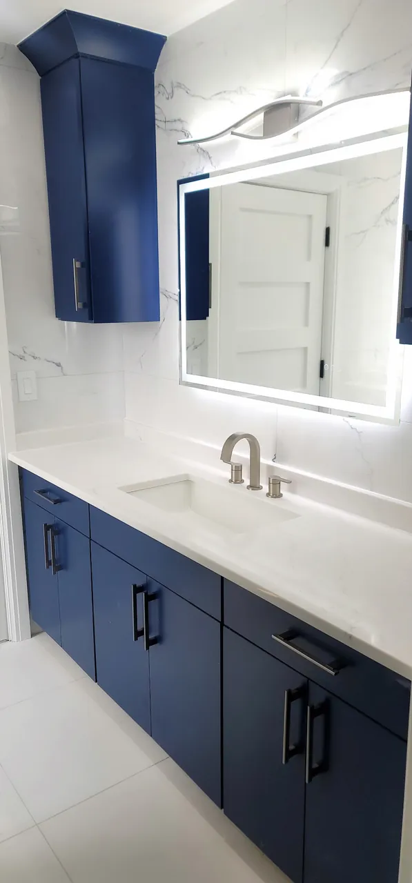 Navy vanity with a lit mirror and a wall cabinet by Mason Oak Carpentry in Detroit, MI