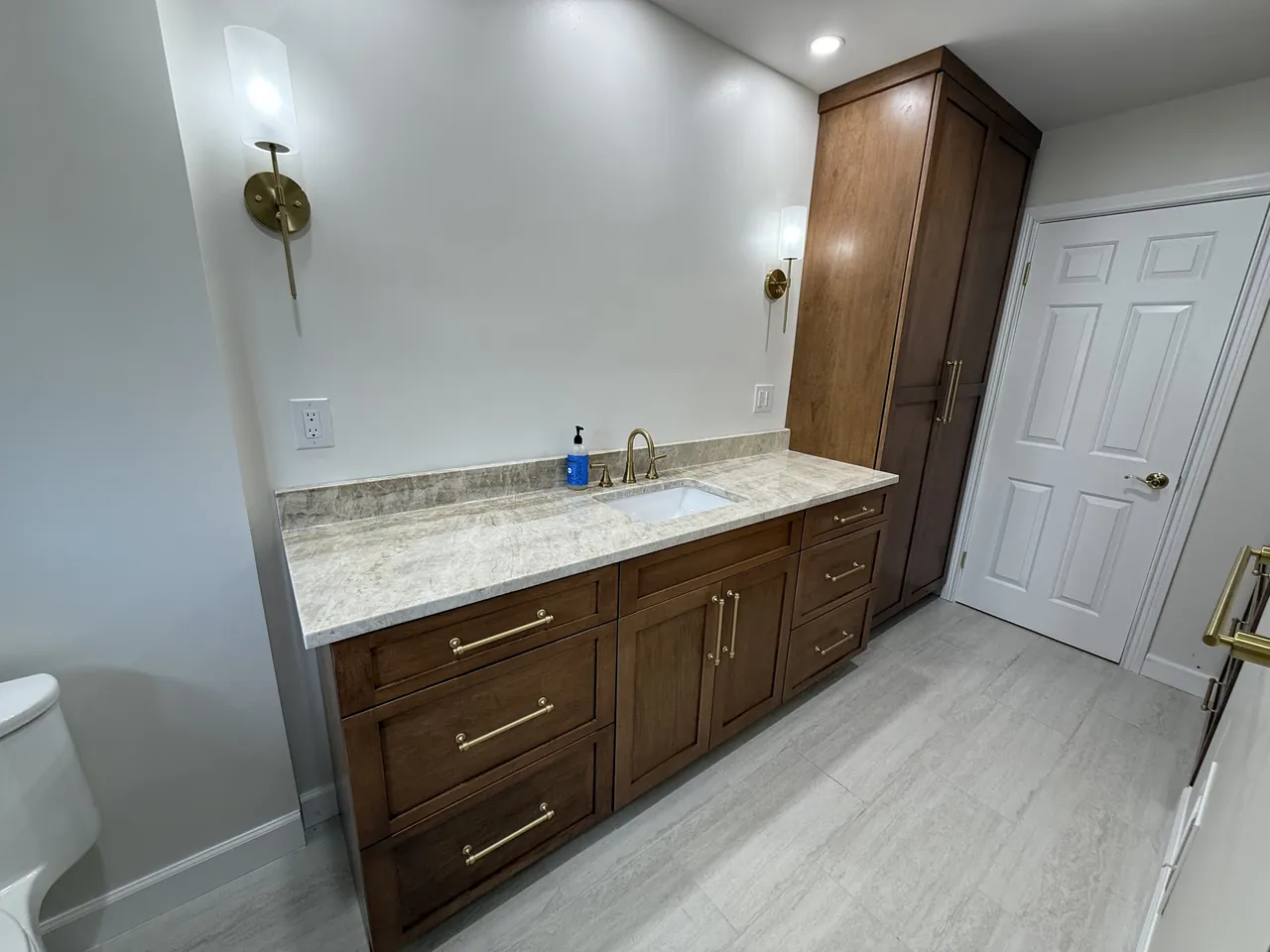 Walnut vanity with brass pulls and a tall linen cabinet by Mason Oak Carpentry in Detroit, MI